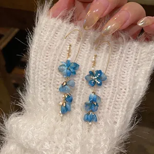 Exquisite blue gradient flower and pearl ear hooks displayed on a cozy white sleeve