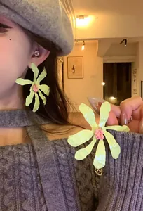 Detailed view of oversized light green flower earrings with pink center on an Asian model