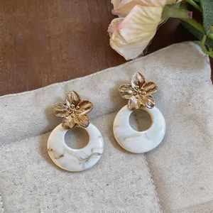 Detailed view of French retro gold flower earrings with marble pattern resin rings.