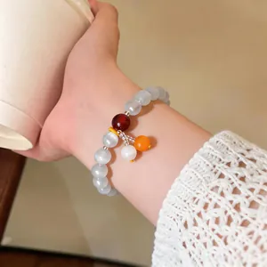 Primo piano dettagliato di un bracciale retrò in perle occhio di gatto indossato al polso