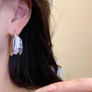 Primo piano di un orecchino a conchiglia d'argento con perline di perle
