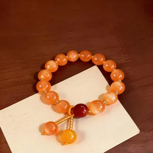 Primo piano di un bracciale vintage con perle occhio di gatto arancione su legno.