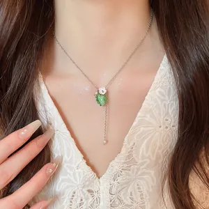 Primo piano della collana con ciondolo a uva verde gelatina e fiore su modella
