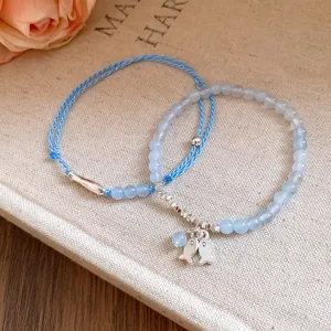 Vista detallada de pulsera de cuentas azul claro con dijes de peces plata