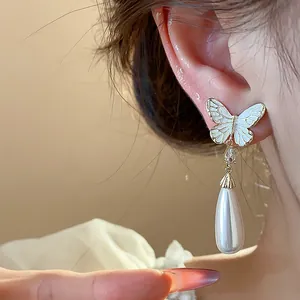 Nahaufnahme eleganter Schmetterlingsohrringe mit Perlenanhänger in 14K Vergoldung