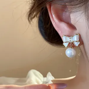 Detailaufnahme eines eleganten 14K vergoldeten Schleifen-Ohrrings mit einer weißen Perle