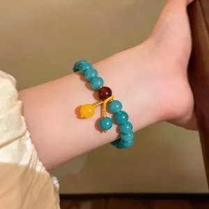 Dettaglio ravvicinato di bracciale etnico con turchese e pietre occhio di gatto.