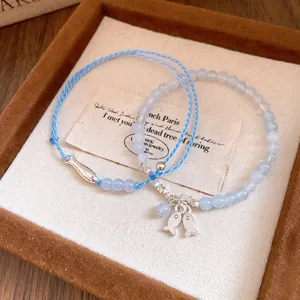 Detalle de la pulsera de cuentas azul claro y cuerda trenzada con dijes de peces