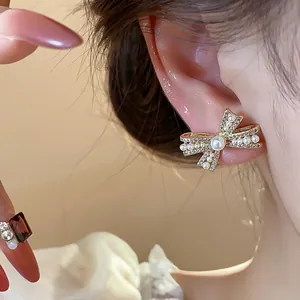 Detailansicht eleganter mit 14 Karat vergoldeter Schleifenohrringe mit Perlen und Kristallen