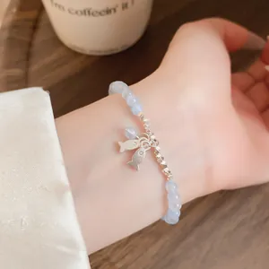 Primer plano de una pulsera de cuentas de piedra azul claro con pequeños peces de plata