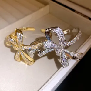 Close-up of elegant gold and silver bow bracelets encrusted with sparkling cubic zircons
