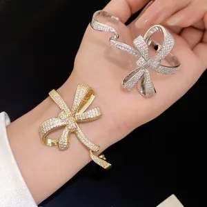 Macro view of glittering gold and silver zirconia bow cuff bracelets on wrist