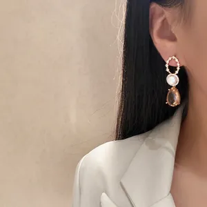 Close-up detail of 18k gold plated zircon pearl drop earrings worn by a chic model