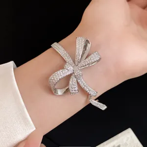 Detailed view of a silver bow bracelet encrusted with sparkling zircons on a wrist.