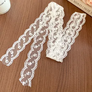 Close-up detail of white floral lace ribbon featuring a woven Love pattern on wood background