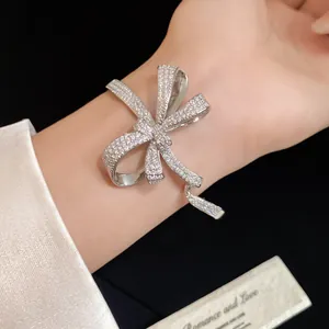 Close-up of elegant silver bow bracelet with pavé cubic zirconia stones on female wrist