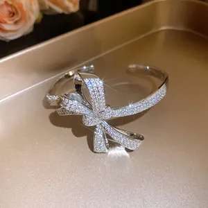 Close-up of elegant silver-colored bow bangle encrusted with sparkling zircons.