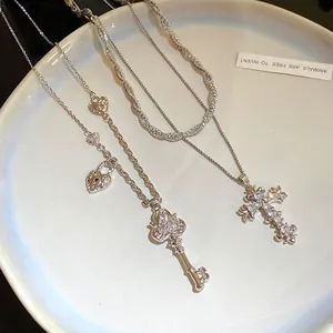 Macro detail of zircon encrusted cross and vintage heart key pendants on silver necklaces