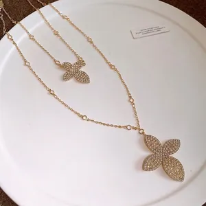 Elegant double-layer gold necklace with rhinestone flower pendants on a white porcelain plate.