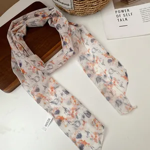 Close-up of floral chiffon neck scarf with delicate orange and purple patterns