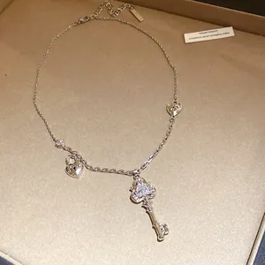 Close-up detail of silver key and heart lock pendant necklace with sparkling zircon pavé