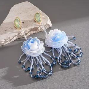 Close-up of elegant blue resin flower earrings with pearl and beaded tassels
