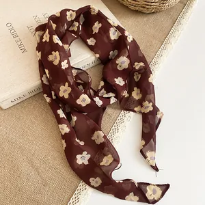 Detailed shot of a burgundy chiffon neck scarf featuring a cream floral print and soft texture