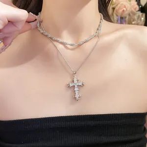 Detail view of ornate zircon cross pendant necklace worn on elegant model's neckline