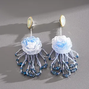 Close-up view of elegant resin flower earrings with intricate blue crystal beaded tassels.