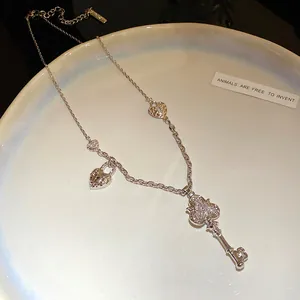 Elegant silver zircon key pendant necklace with heart charms on a white ceramic plate
