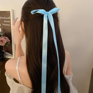 Back view of a sweet light blue satin ribbon bow hair clip on long wavy brown hair