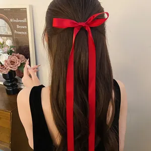 Close-up of a sweet red ribbon bow hair clip with long streamers in balletcore style