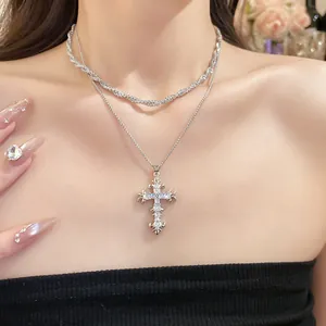 Detailed view of layered silver-tone necklace featuring a vintage zircon-inlaid cross pendant.