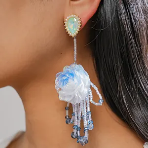 Detailed close-up of blue resin flower earring with long beaded tassels and pearls.