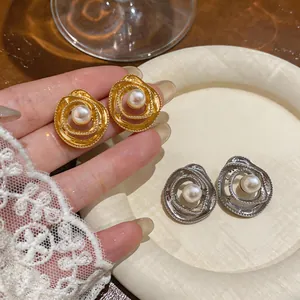Dettaglio di eleganti orecchini a perno a forma di fiore cavo con perla centrale