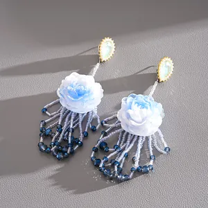 Detail of elegant resin flower tassel earrings with blue gradient beads and silver pins.