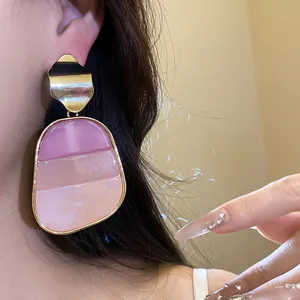 Primer plano de pendiente vintage de resina rosa y oro en modelo para ver detalles