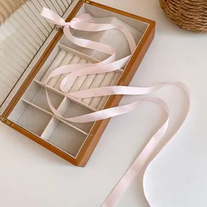 Sweet pink balletcore ribbon hair accessory elegantly draped over a wooden jewelry box
