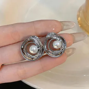 Dettaglio di orecchini a fiore in argento con perle bianche tenuti in mano