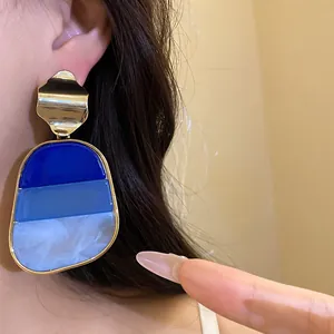 Primer plano de pendientes retro con colgantes de resina en degradado azul triple