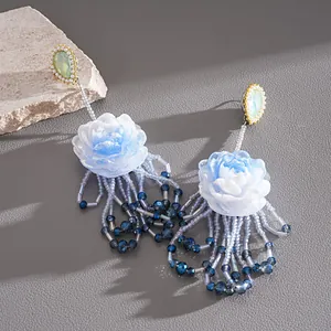 Detailed macro view of elegant blue resin flower tassel earrings with pearls and crystals