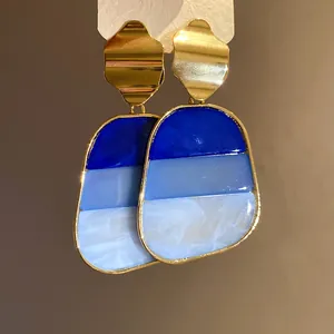 Detalle de pendientes vintage de resina azul con degradado y elegantes tachuelas doradas