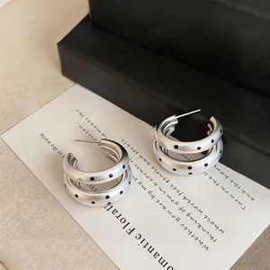 Detailed view of silver multi-layer earrings with black polka dots in retro style.