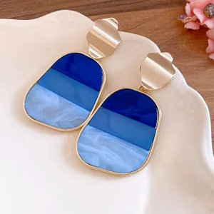 Primer plano de pendientes vintage dorados con colgantes de resina degradados azules