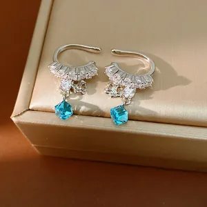 Close-up detail of silver iris flower ear cuffs with sparkling blue cube crystals