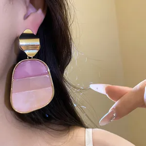 Primer plano de pendientes retro de resina rosa con detalle dorado en una modelo