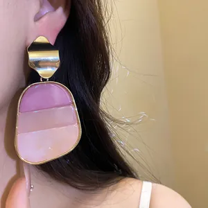 Primer plano de pendiente vintage con colgante de resina rosa degradado y metal dorado