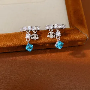 Elegant zircon fleur-de-lis ear clips with light blue square crystal drops for women.