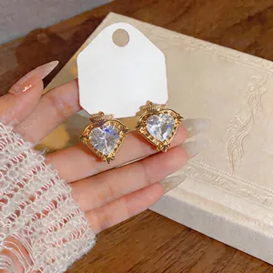 Nahaufnahme eleganter herzförmiger Zirkon-Ohrringe mit verzierten goldfarbenen Rändern.