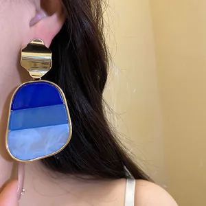 Primer plano de pendientes vintage con degradado de resina azul y detalles dorados